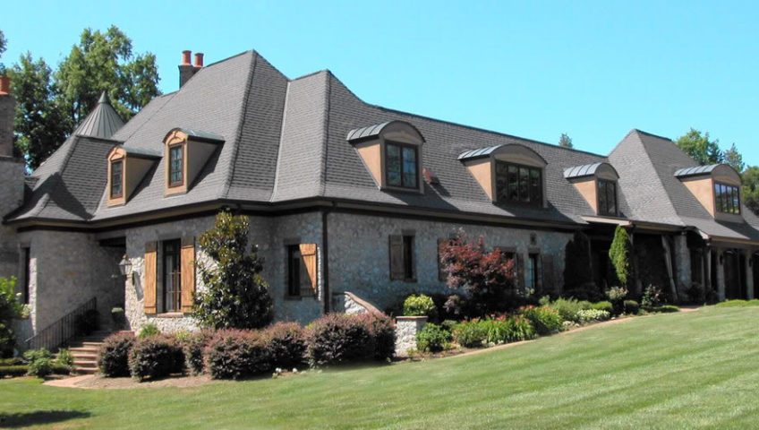 Elegant stone house with a slate roof and manicured lawn.